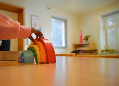 Kind im Kindergarten mit Regenbogen-Spielzeug